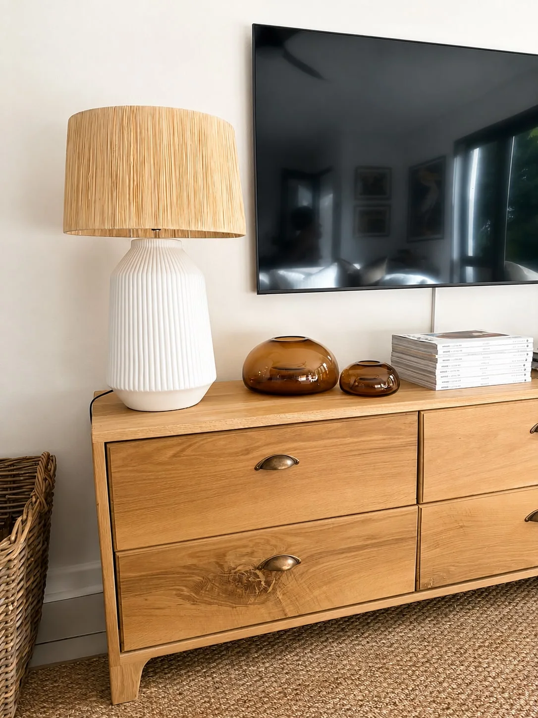 Pence House living room — light-oak sideboard with a ribbed ceramic lamp, amber glass and layered natural textures